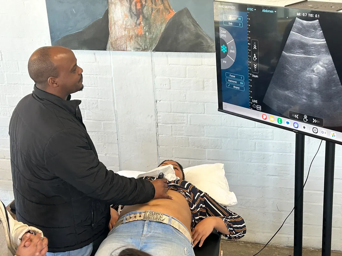 Instructor performing an abdominal ultrasound scan with the live image on a large display