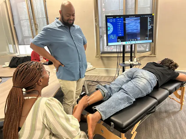 Instructor guiding a learner through a musculoskeletal calf scan with the live image on screen